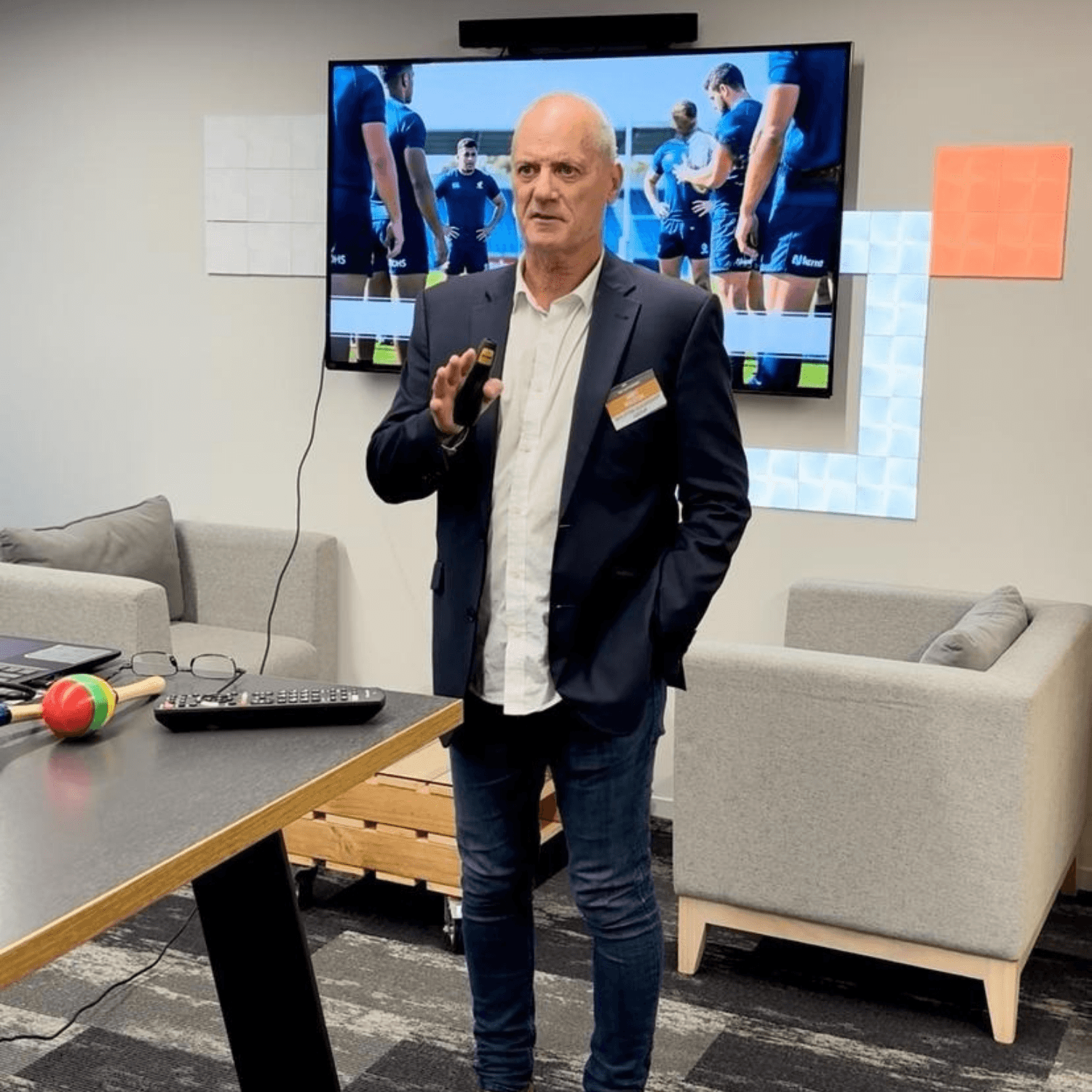 Andy presenting to managers in front of a screen showing a rugby team